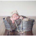 newborn in bucket with cute hat