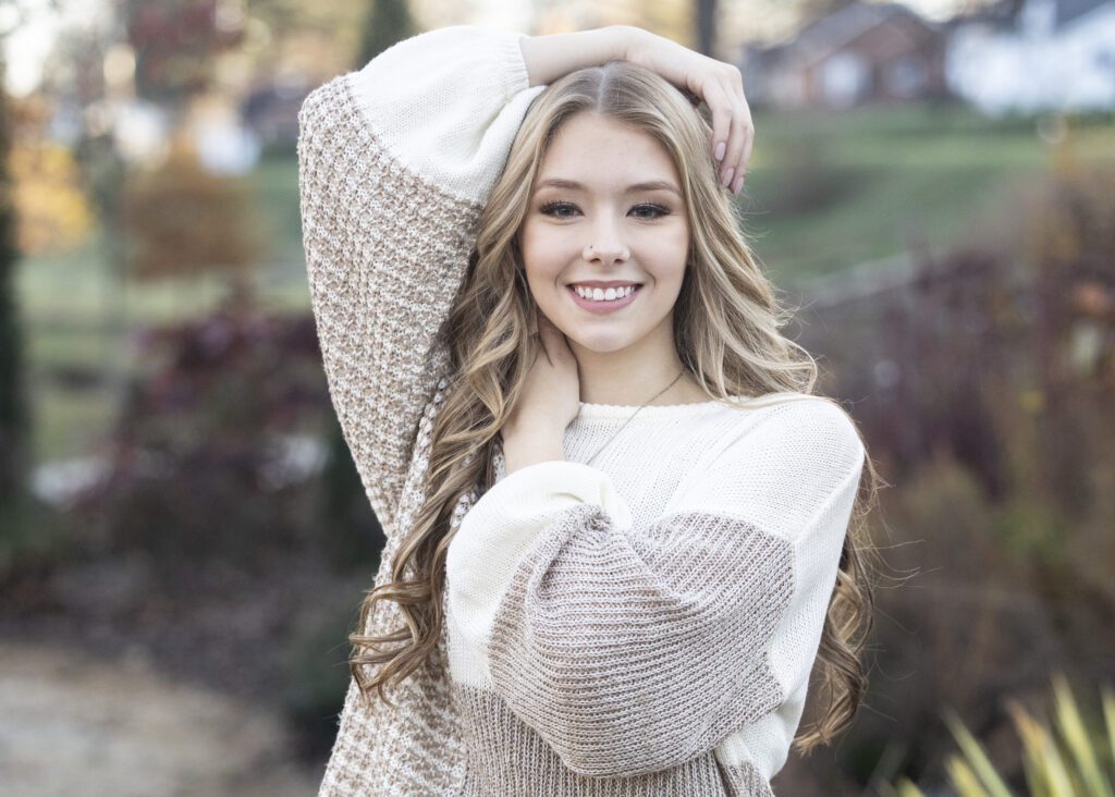 High school senior girl smiling in front of fall foliage in Chapel Hill